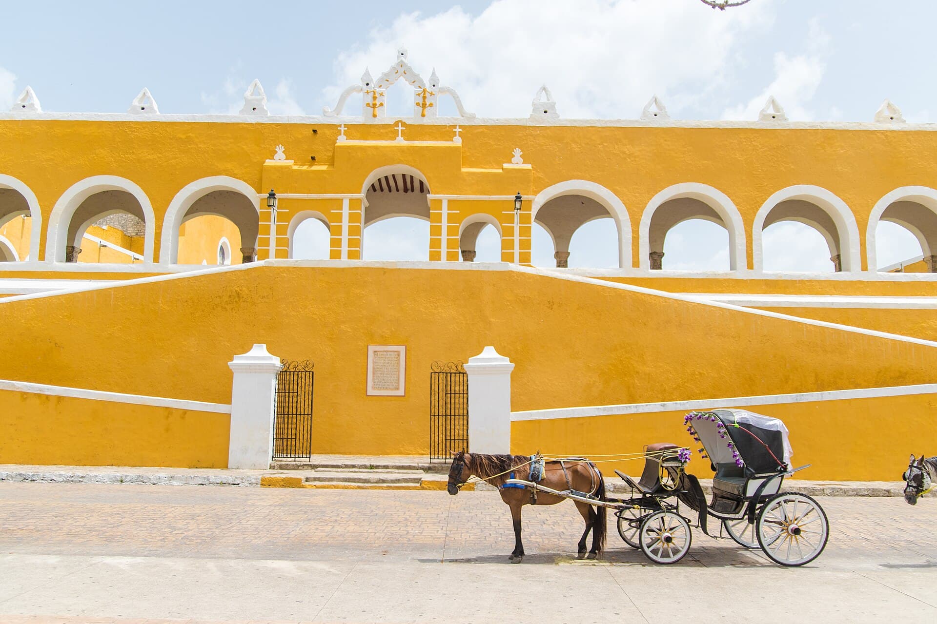 Yellow convent walls and a horse carriage in Izamal